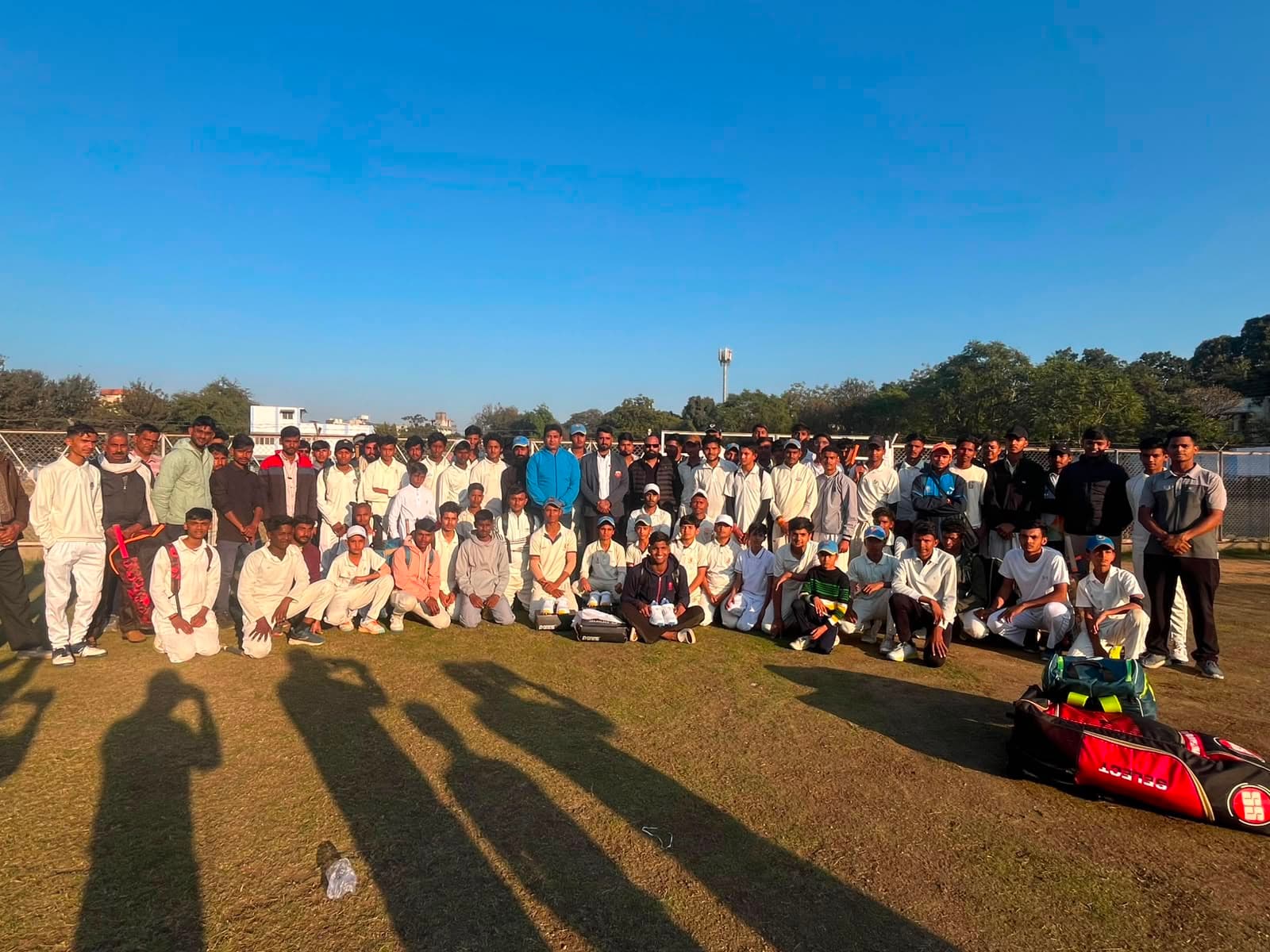 Grassroots cricket team and coaches posing together on the ground